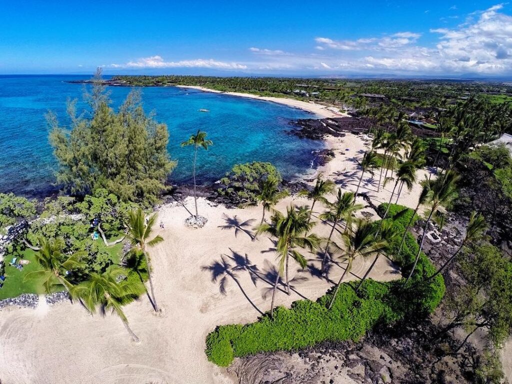 Calm lagoon with gentle waves and shaded palm trees at Kikaua Point Beach Park