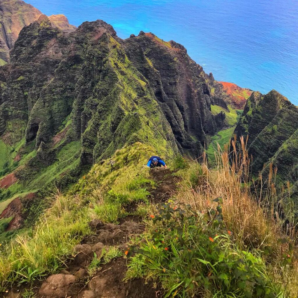 Hiker walking along ridge trail at Koke’e State Park overlooking valley