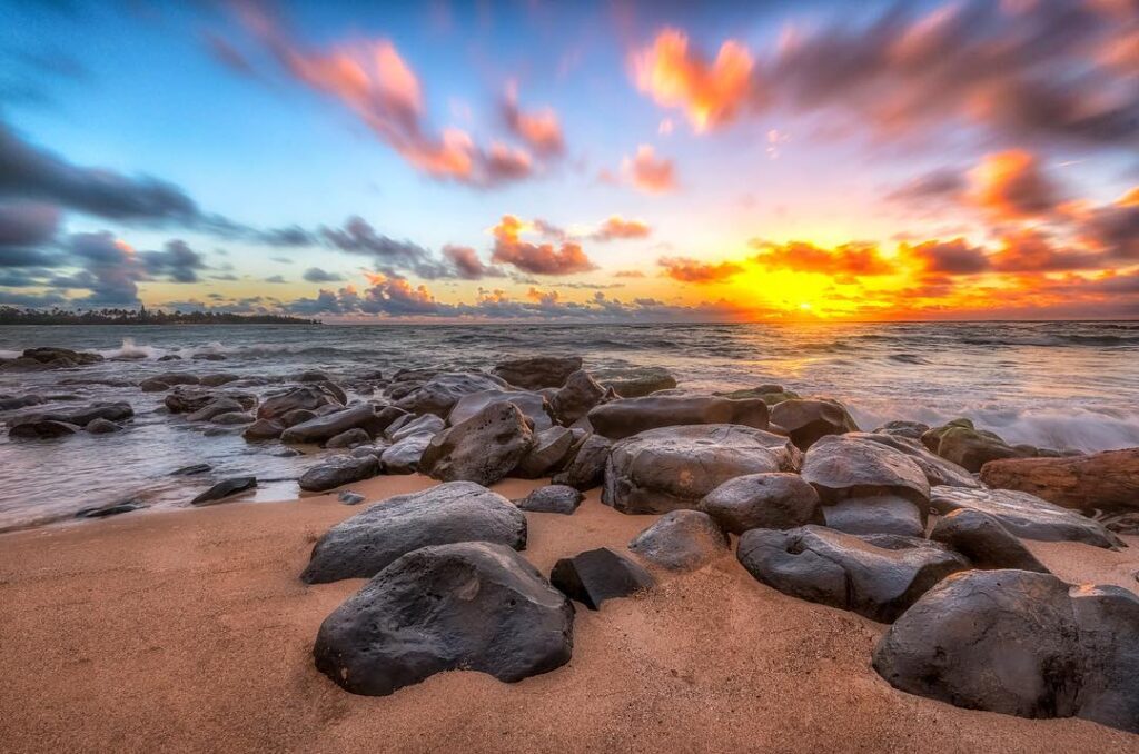 Sunrise over calm waters at Lydgate Beach with pastel sky