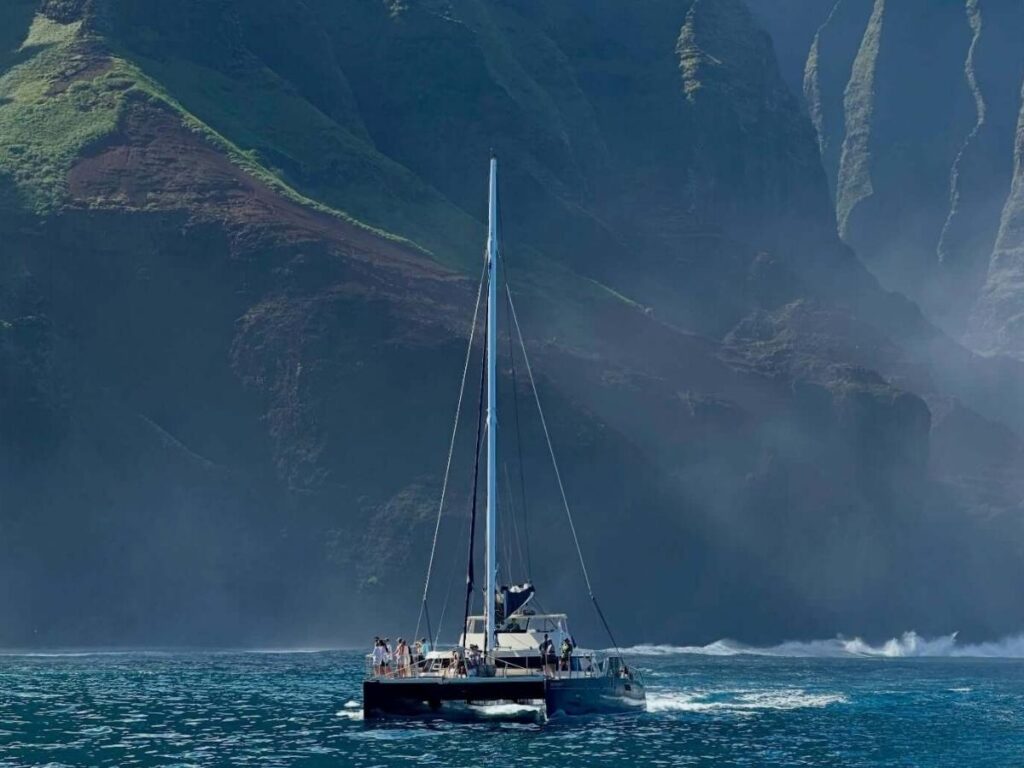 Boat tour traveling along the Na Pali Coast cliffs in Kauai Hawaii