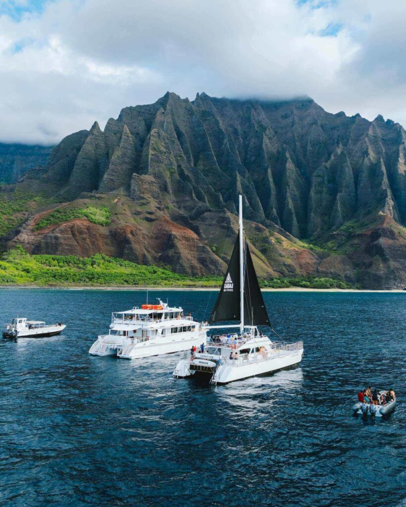 Catamaran sailing beneath the towering cliffs of the Na Pali Coast on Kauai