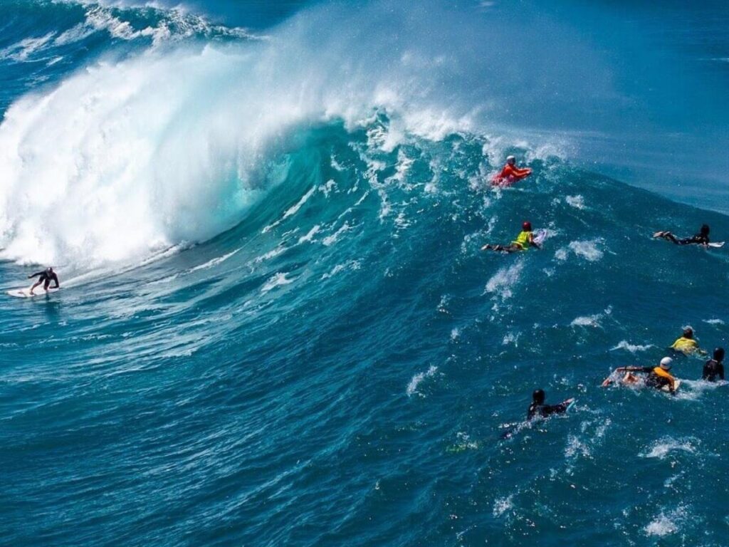 Large winter waves on Oahu’s North Shore with surfers in the distance