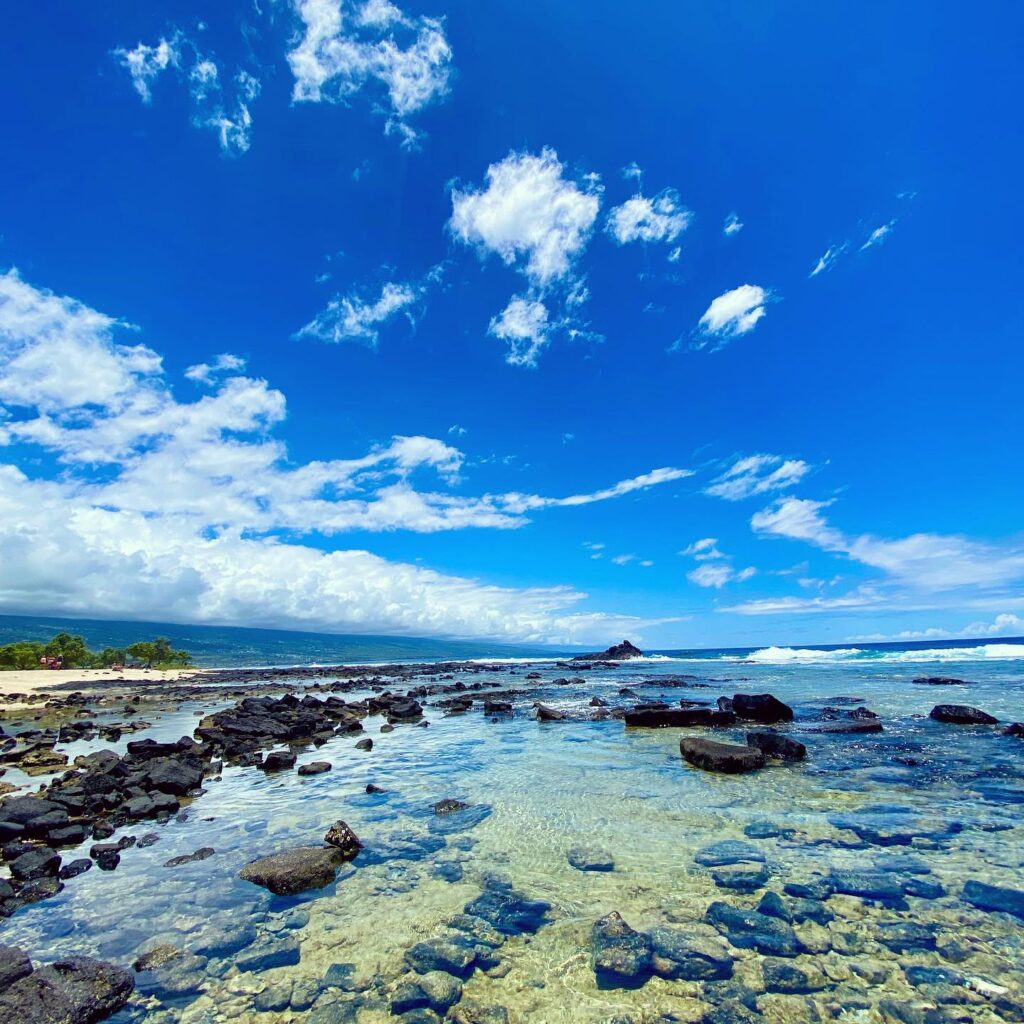 Wide sandy stretch with lava rocks and calm surf at Old Kona Airport Beach