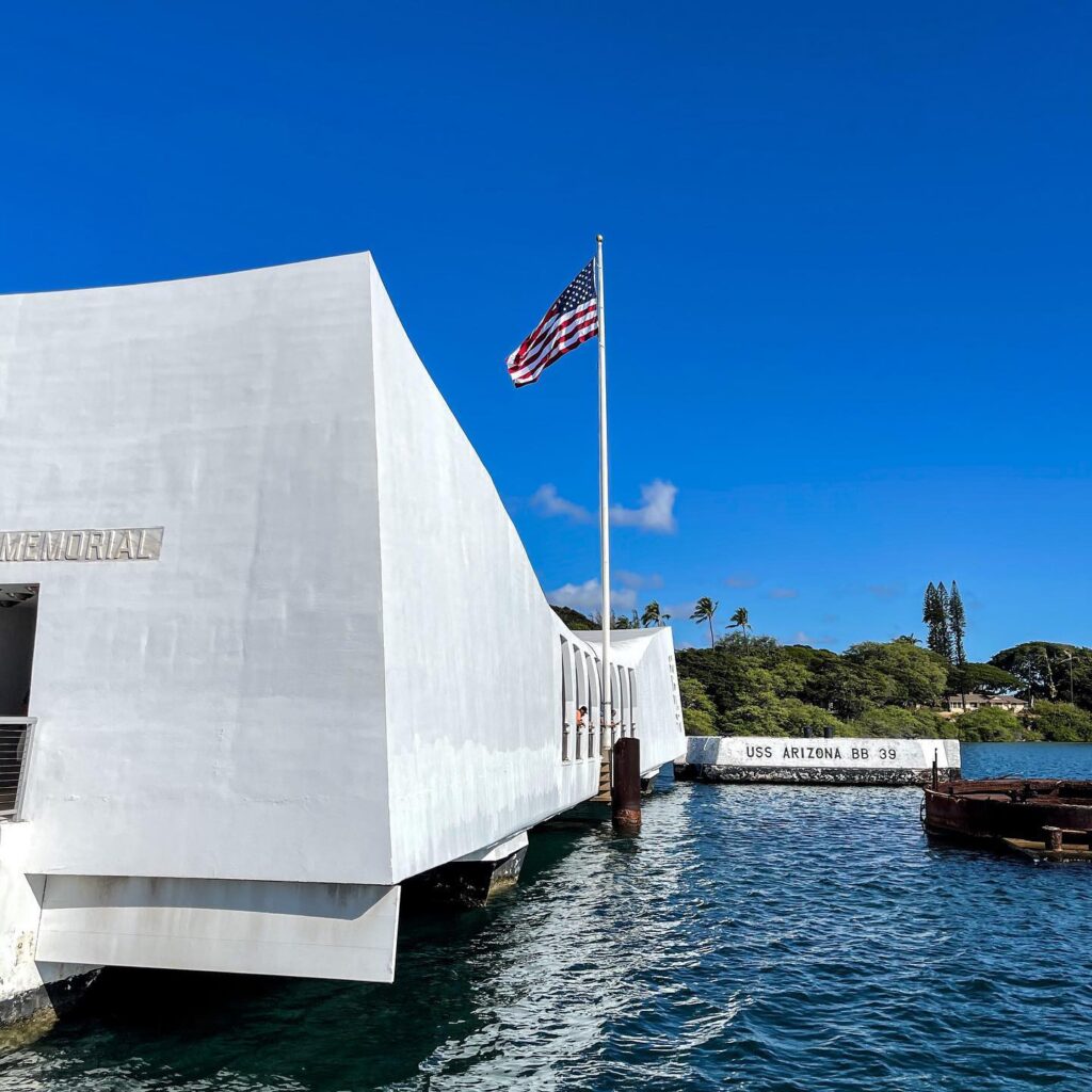White structure of USS Arizona Memorial floating above sunken battleship