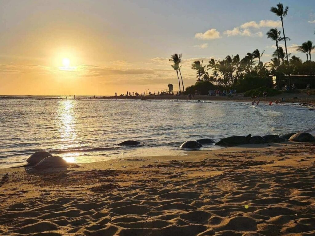 Sunset over Poipu Beach on Kauai with golden sky and gentle waves