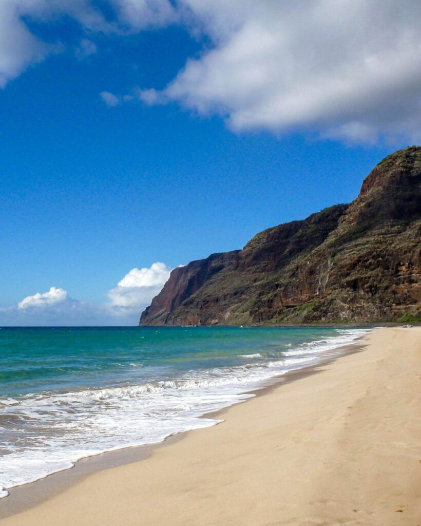 Wide, uncrowded shoreline at Polihale State Park with the Nā Pali Coast in the distance