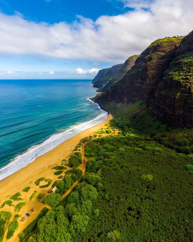 Wide sandy beach and dunes at Polihale State Park with cliffs in distance