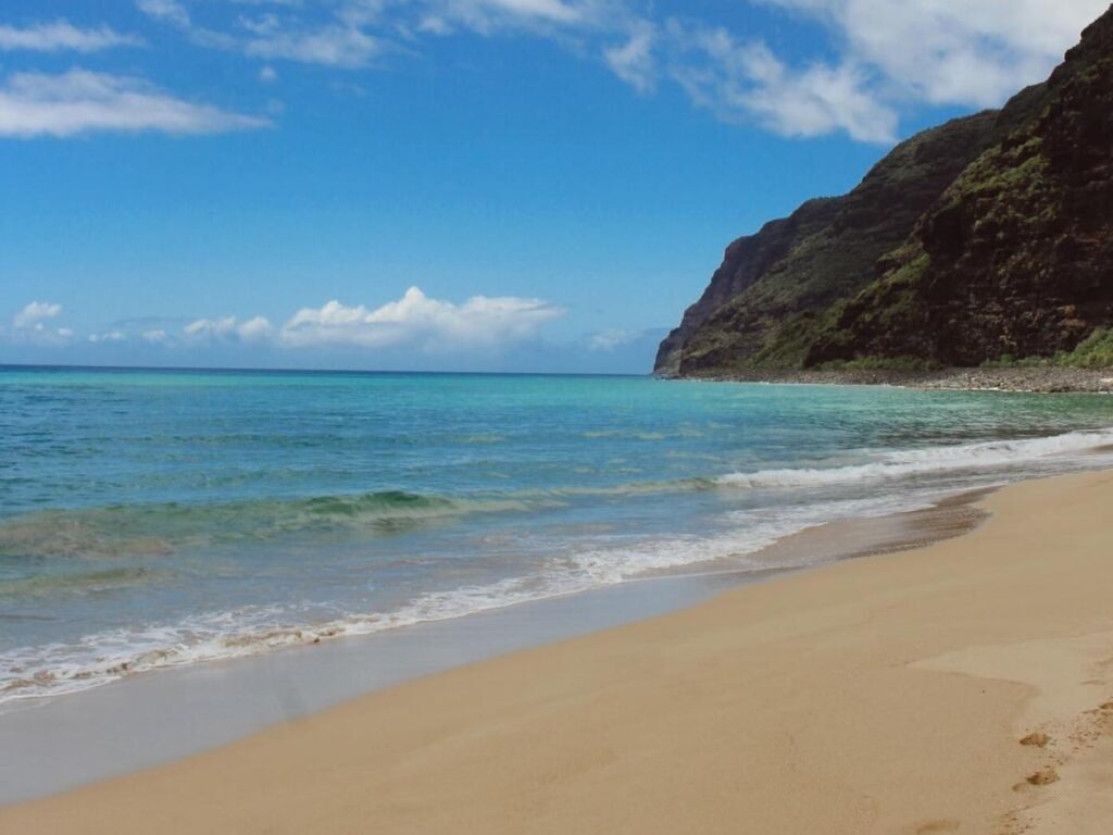 Long sandy beach at Polihale State Park with Na Pali cliffs in the distance