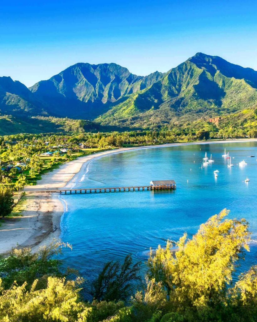 Scenic coastal road surrounded by tropical rainforest and mountains on Kauai