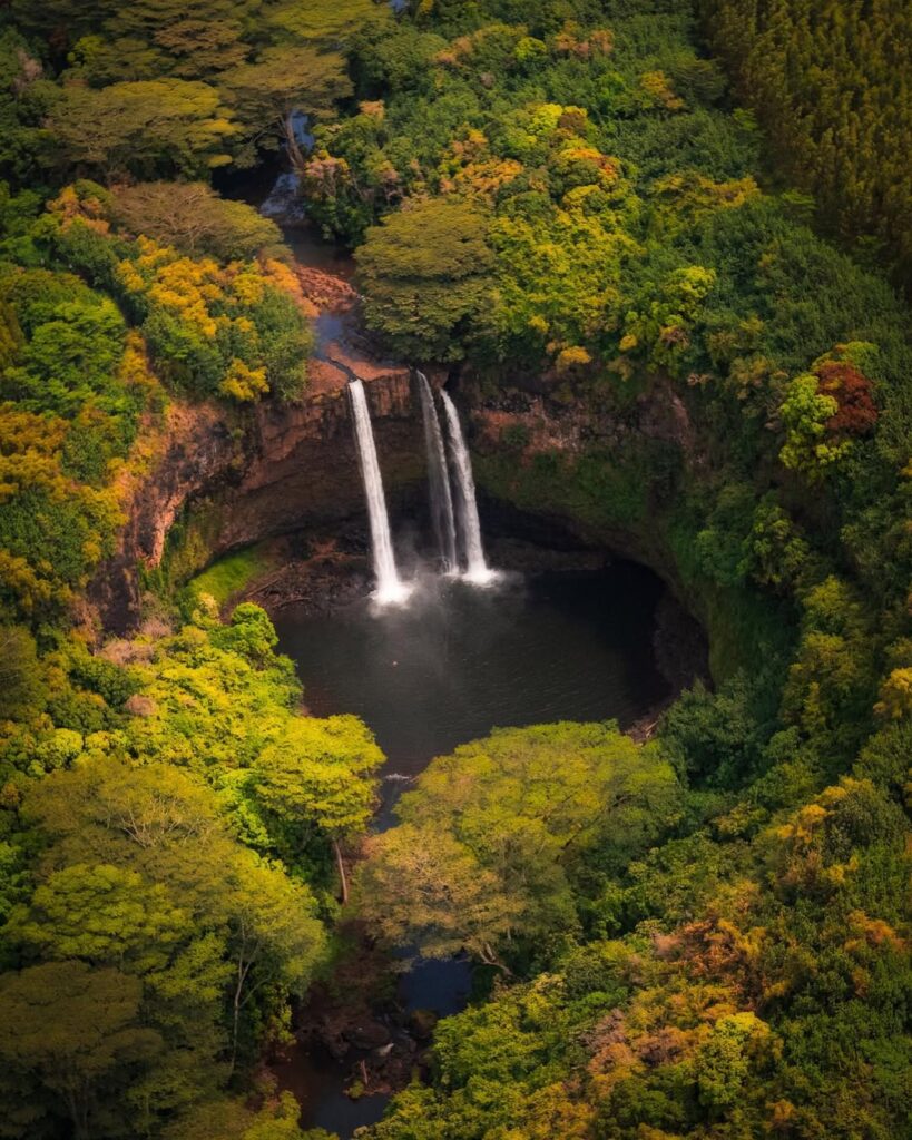 Twin waterfalls of Wailua Falls cascading into a misty pool with rainbow