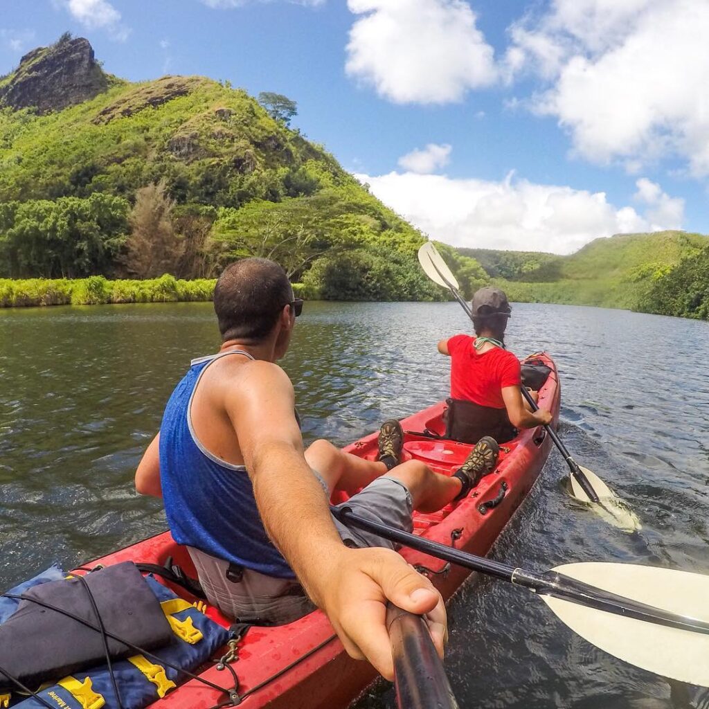 Kayakers paddling along the Wailua River surrounded by lush rainforest