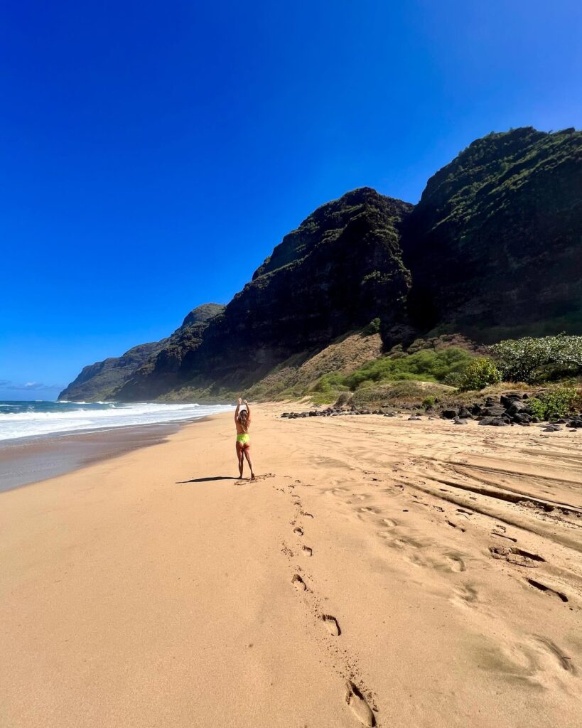 Visitor walking along the long sandy shoreline at Polihale State Park