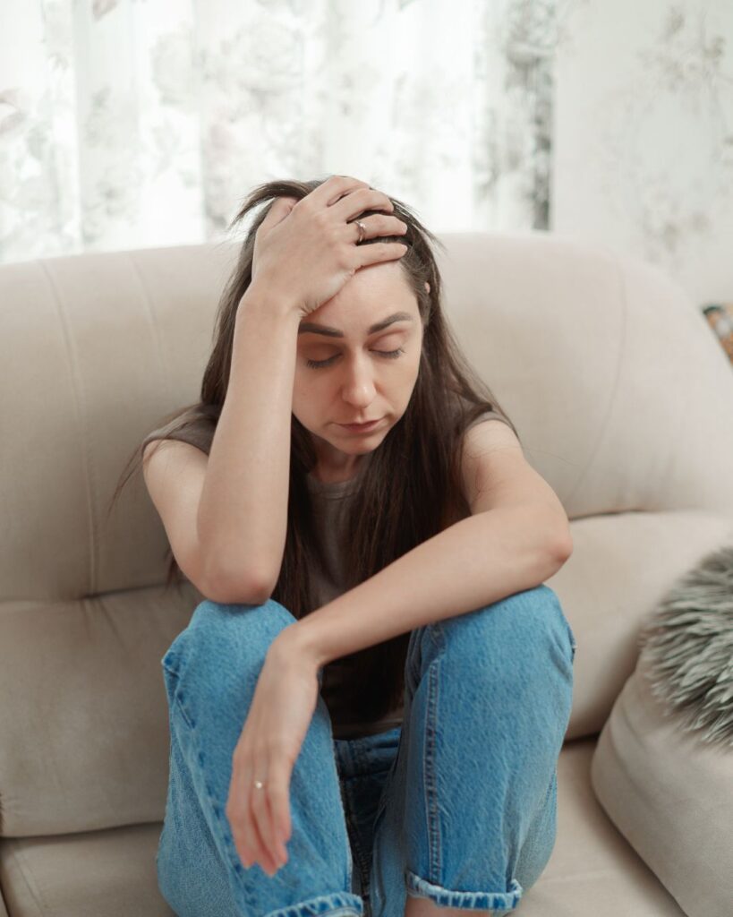 Woman holding her head in discomfort while resting in a hotel room at high altitude
