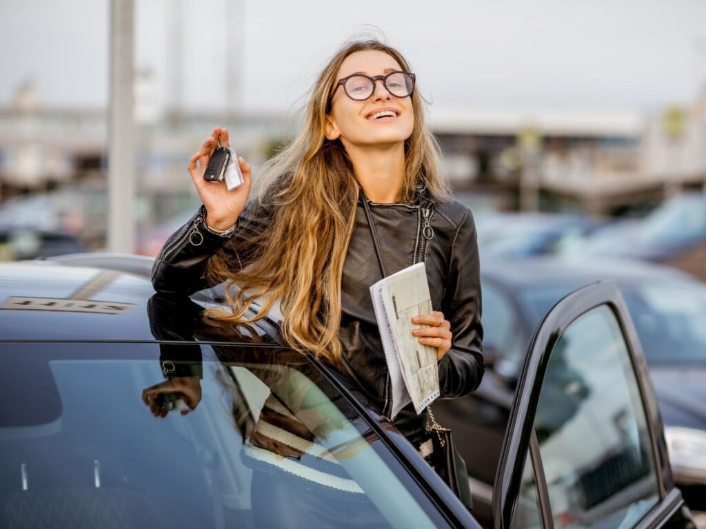 Woman holding car keys next to a rental car