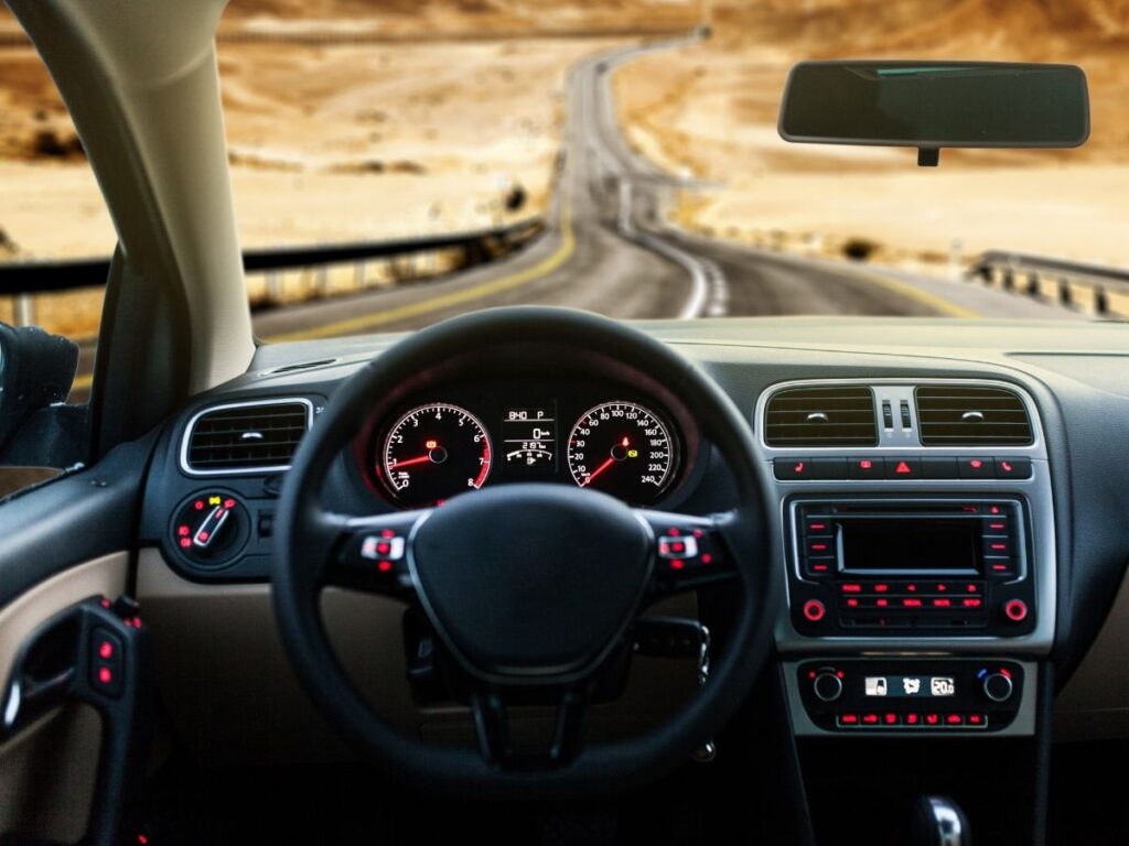 Car dashboard with odometer and open scenic road view