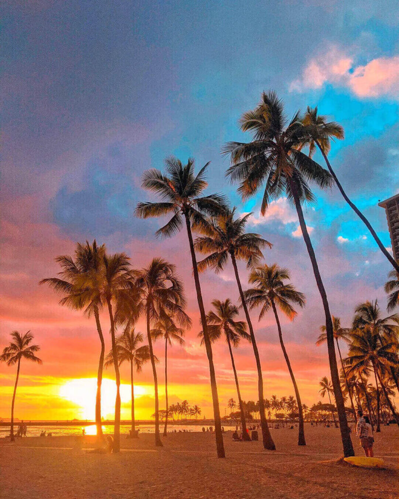 Pink and orange sunset clouds reflecting over the Pacific Ocean at Waikiki Beach