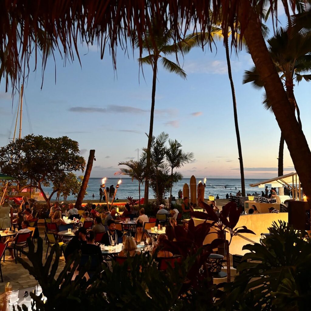 Outdoor dining at Duke's Waikiki overlooking Waikiki Beach at sunset