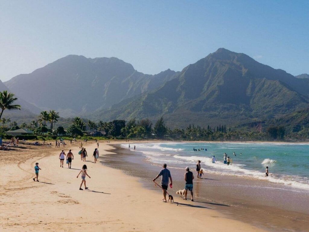 Hanalei Bay in Kauai with a wide beach and green mountains rising behind the shoreline