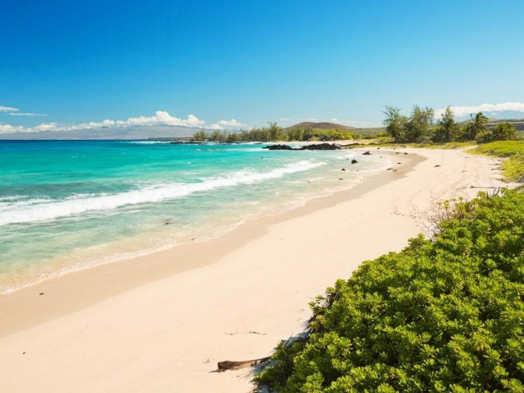 Pale sand and clear water at Makalawena Beach reached by lava rock trail on the Kona side
