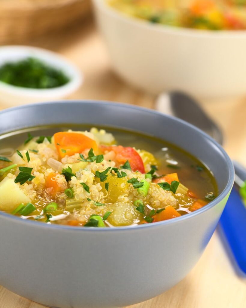 A warm bowl of quinoa soup with bread on the side, served in a rustic Andean café