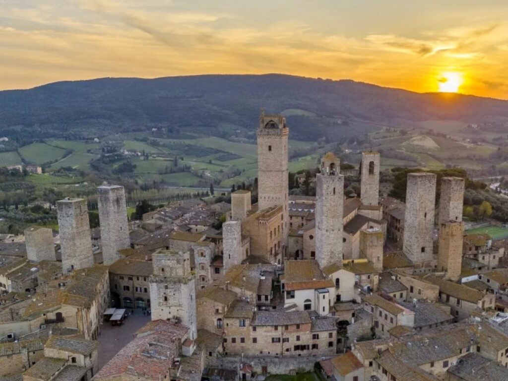 Medieval towers of San Gimignano glowing at golden hour with vineyards below