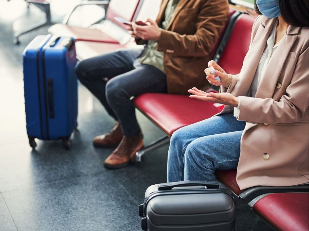 Traveler using a mini spray sanitizer in an airport waiting area
