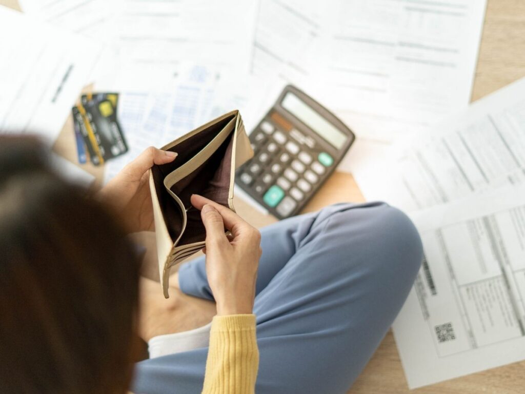 Traveler reviewing vacation expenses next to a suitcase before a trip