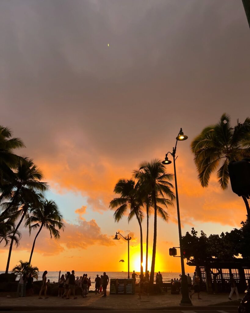 Visitors enjoying a sunset picnic on the grassy lawn at Magic Island