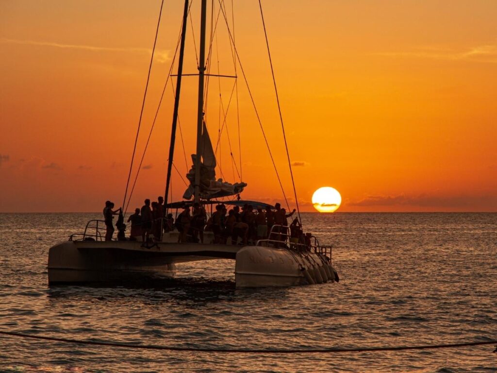 Catamaran sailing off Waikiki Beach during a colorful sunset with Diamond Head in the background