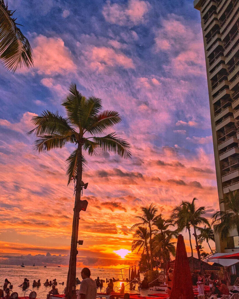 Visitors relaxing on Waikiki Beach while watching the sunset