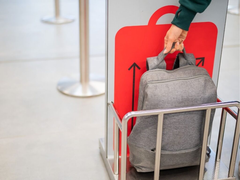 Passenger checking luggage size at an airline bag sizer before boarding.