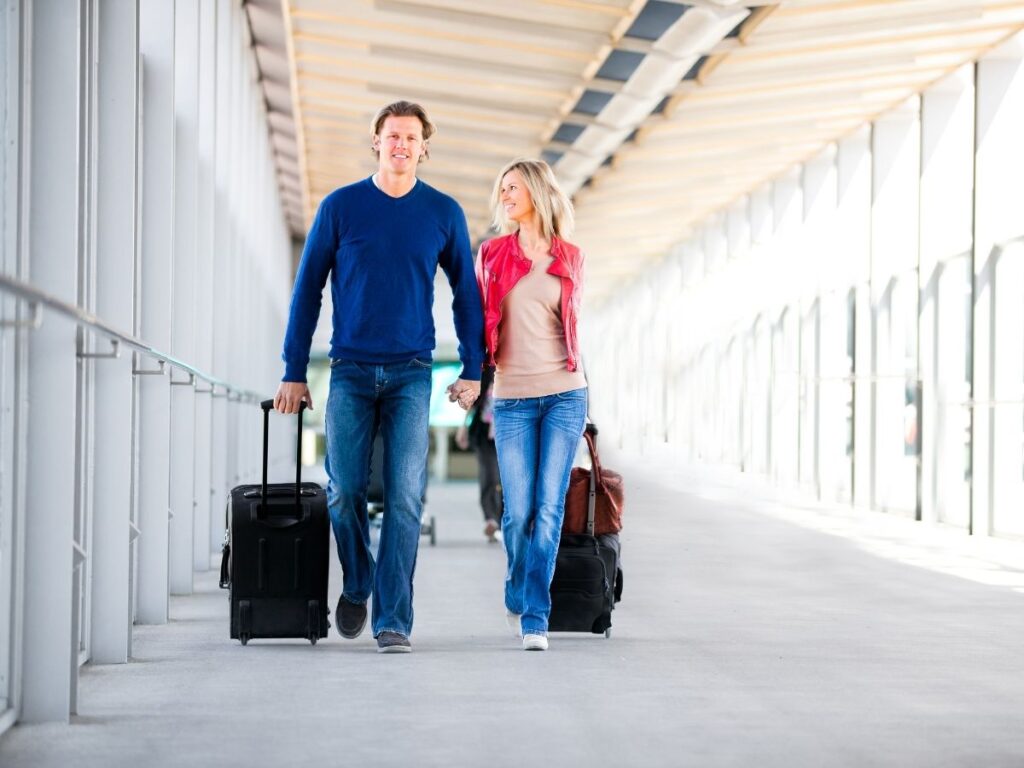 Travellers walking through airport with carry-on bag