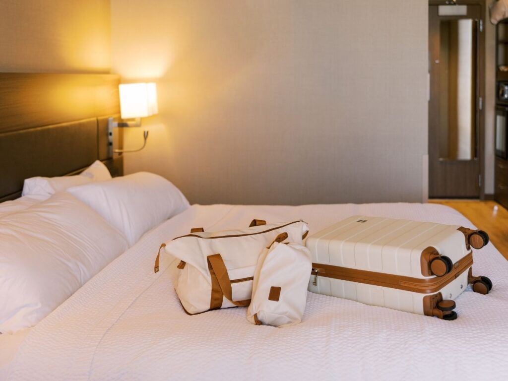 Sleek hard-shell carry-on suitcase and compact under-seat bag placed side by side on a hotel bed