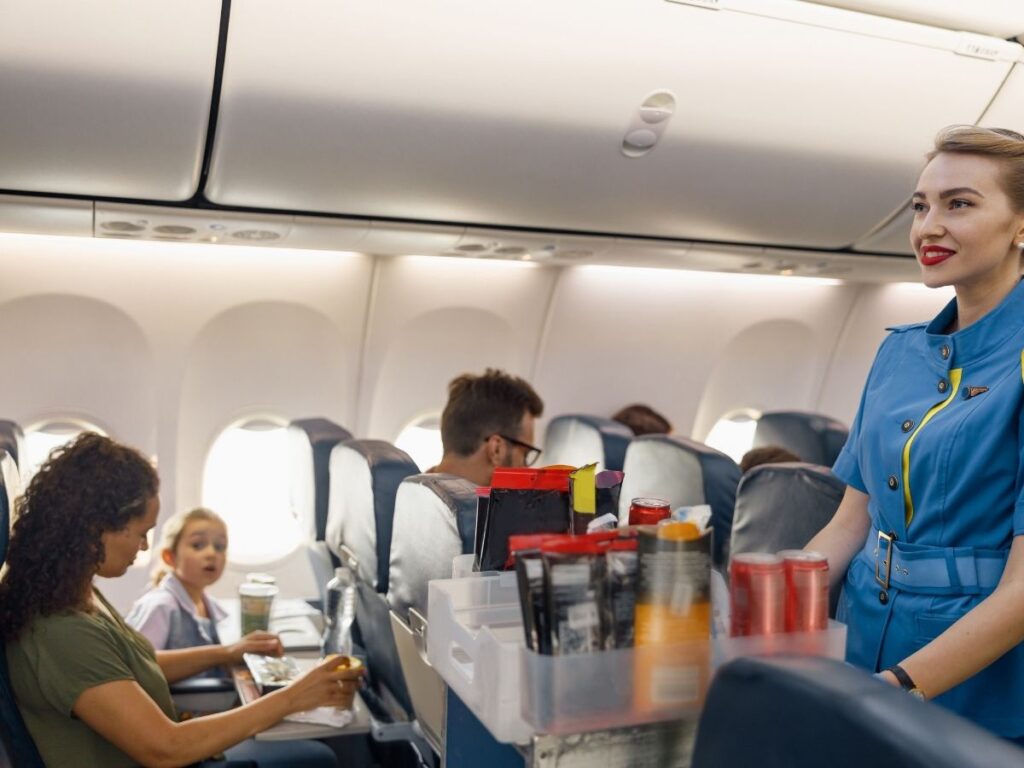Tray table with bottled water and packaged snacks on a budget airline flight.