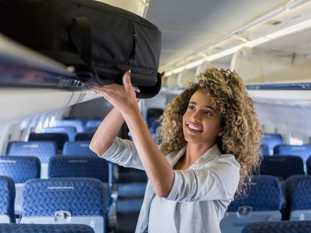 placing a small suitcase in airplane overhead bin