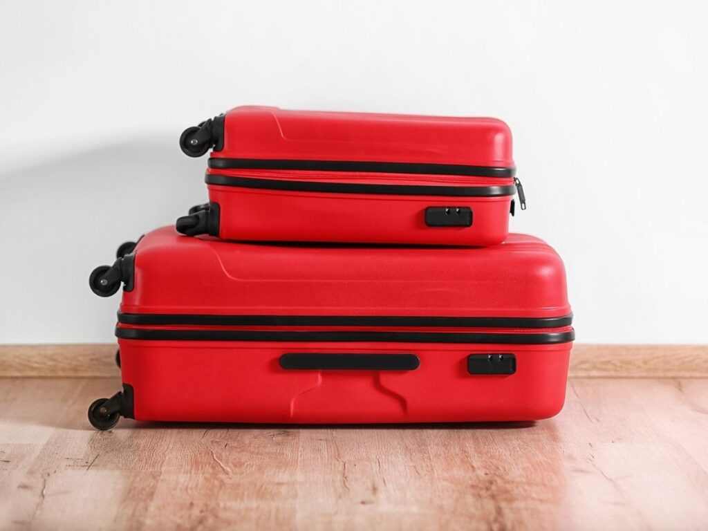 Traveler comparing a small suitcase and a large suitcase at home