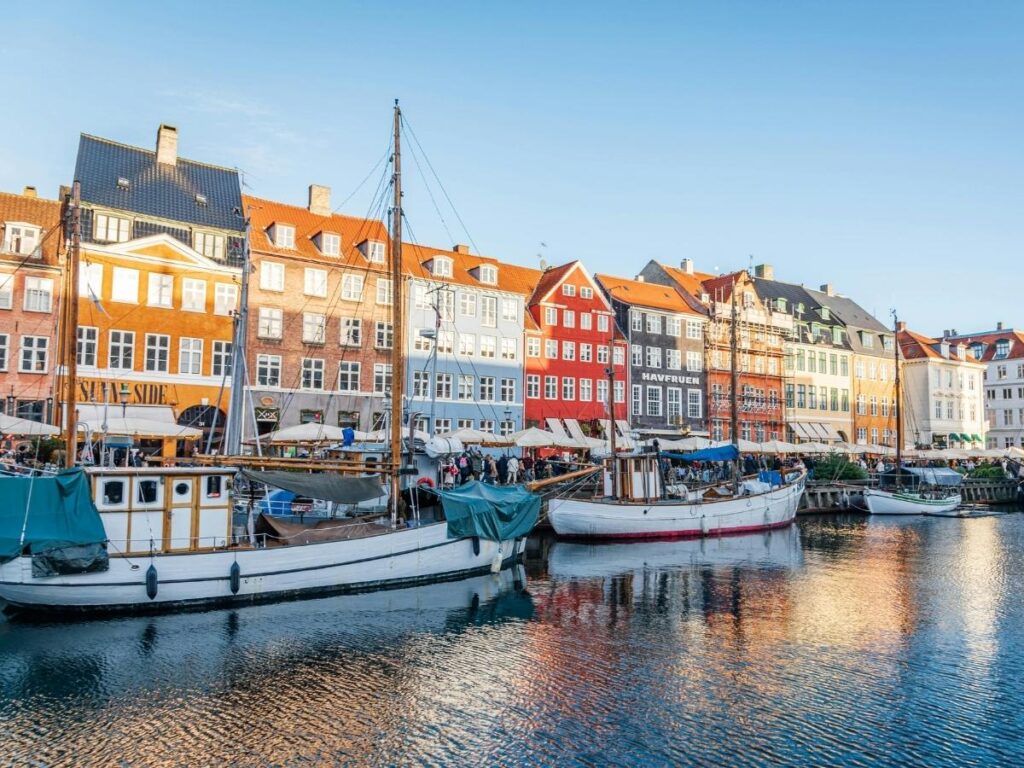 Copenhagen’s Nyhavn harbor with colorful historic houses and boats at sunset.