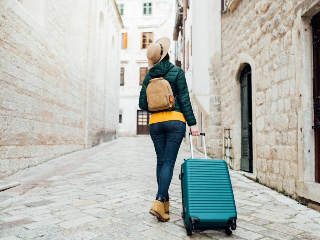 Traveler with luggage standing outside a closed apartment building, realizing the rental listing was fake.