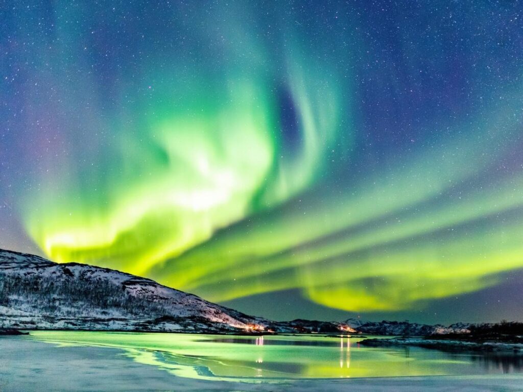 Northern Lights glowing above a snowy log cabin in Finnish Lapland.