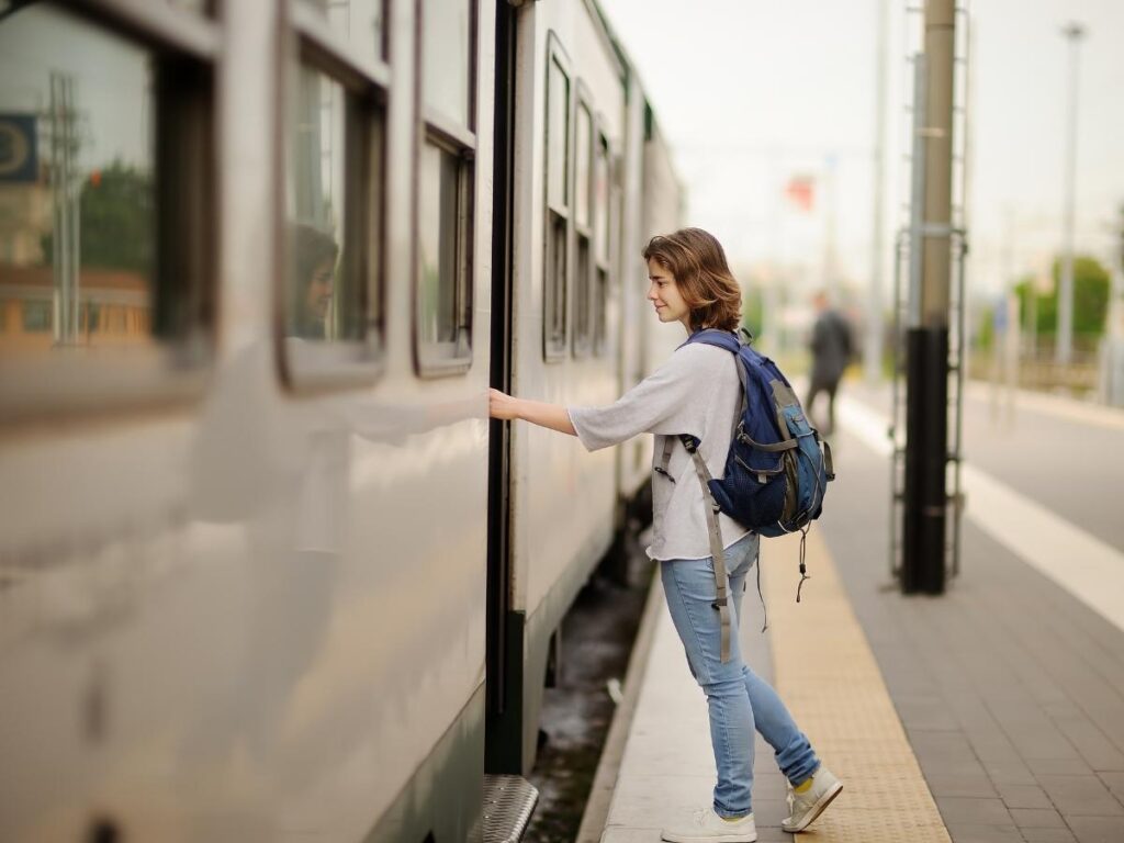 Traveler with a sleek carry-on backpack walking through a European train station, showing the French approach to light packing.