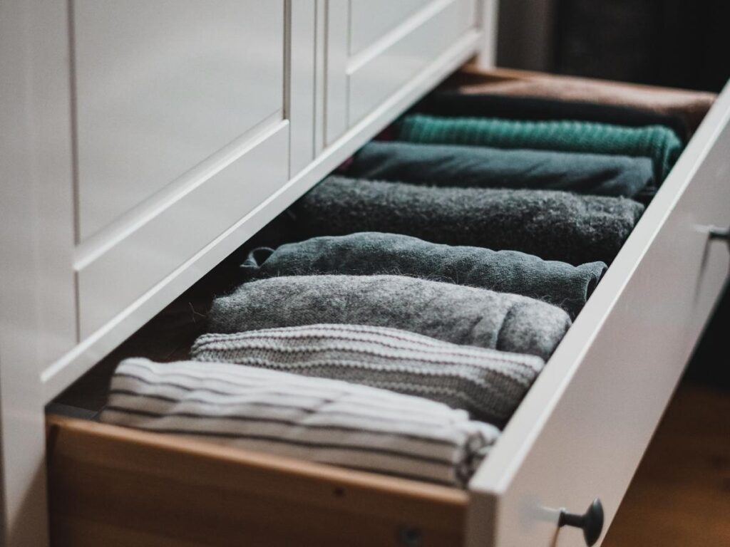 Clothes neatly organized inside a hotel dresser drawer.