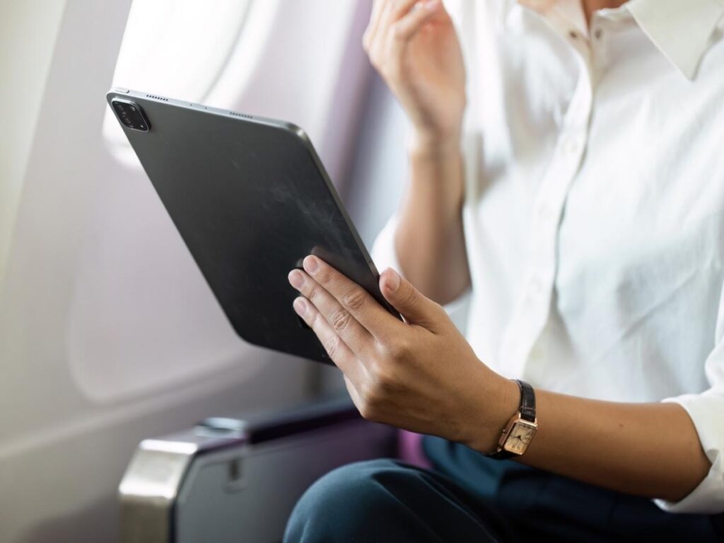 Traveler using a tablet with on a long-haul flight.