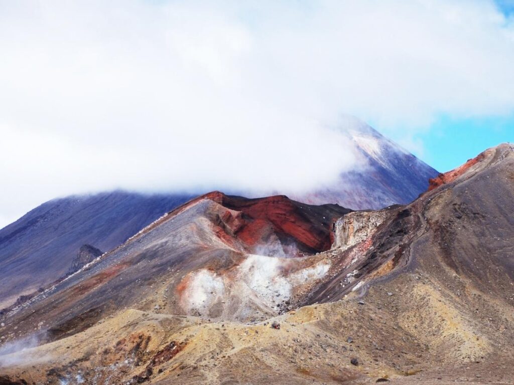 Tongariro Alpine Crossing trail with volcanic peaks in the distance.