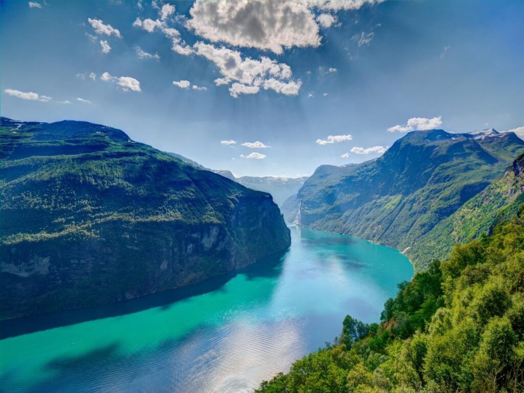 Norway’s Geirangerfjord surrounded by steep green cliffs.