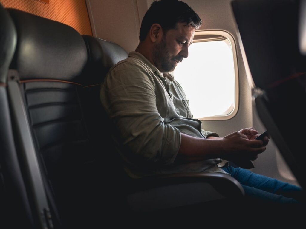 Airplane cabin with passenger using phone in airplane mode