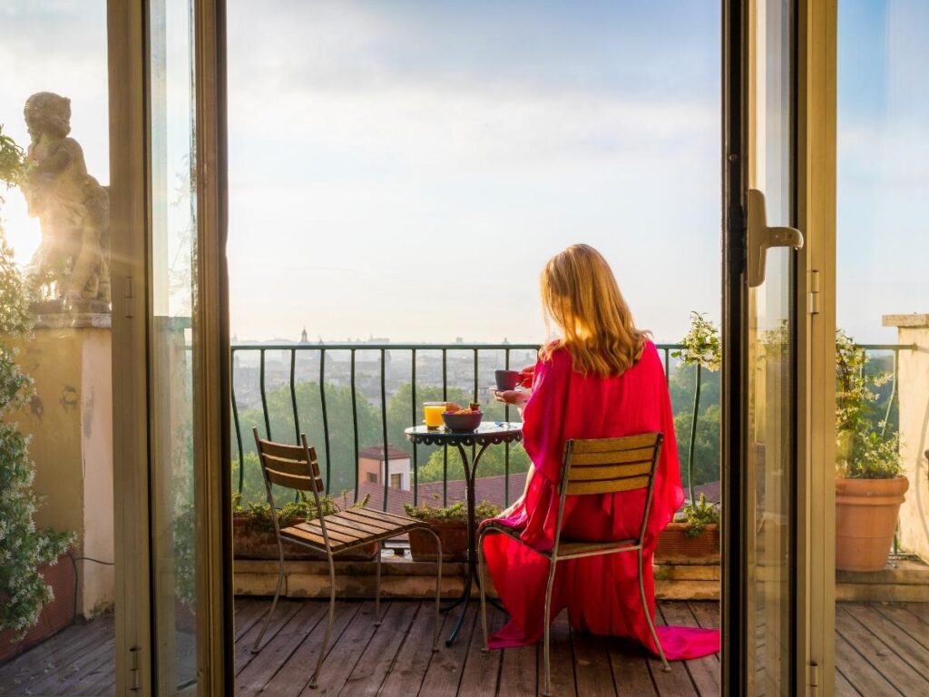 Traveler enjoying coffee on a hotel balcony with a scenic view.