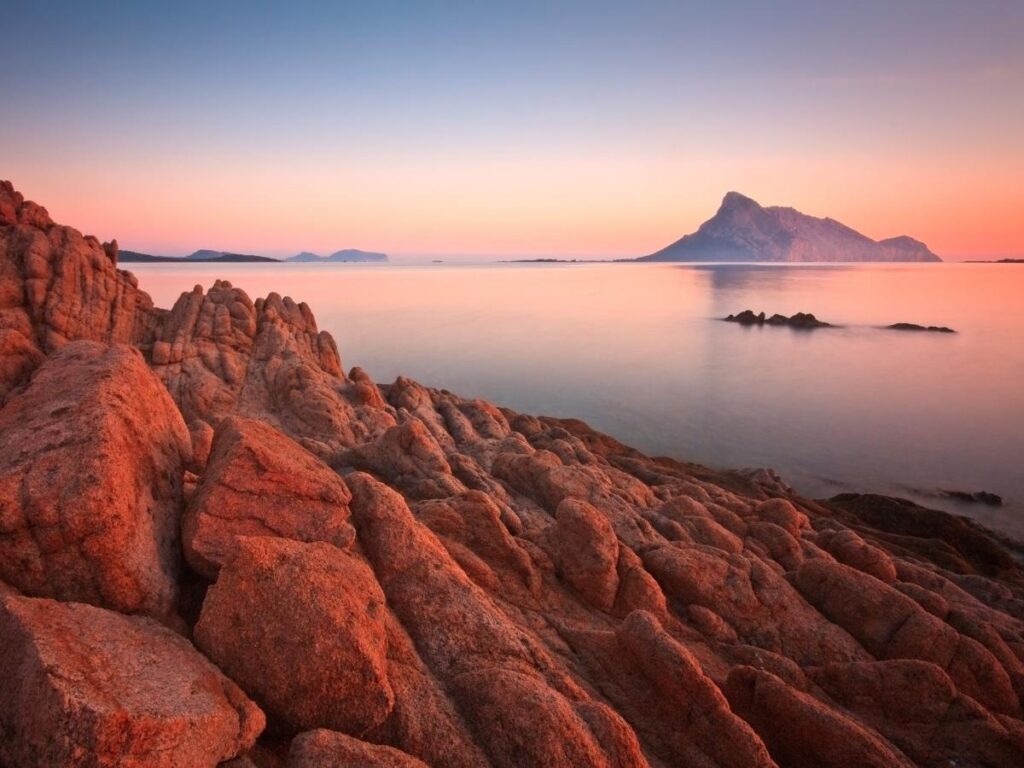 Sunset over Sardinia’s rugged coastline with cliffs and calm sea