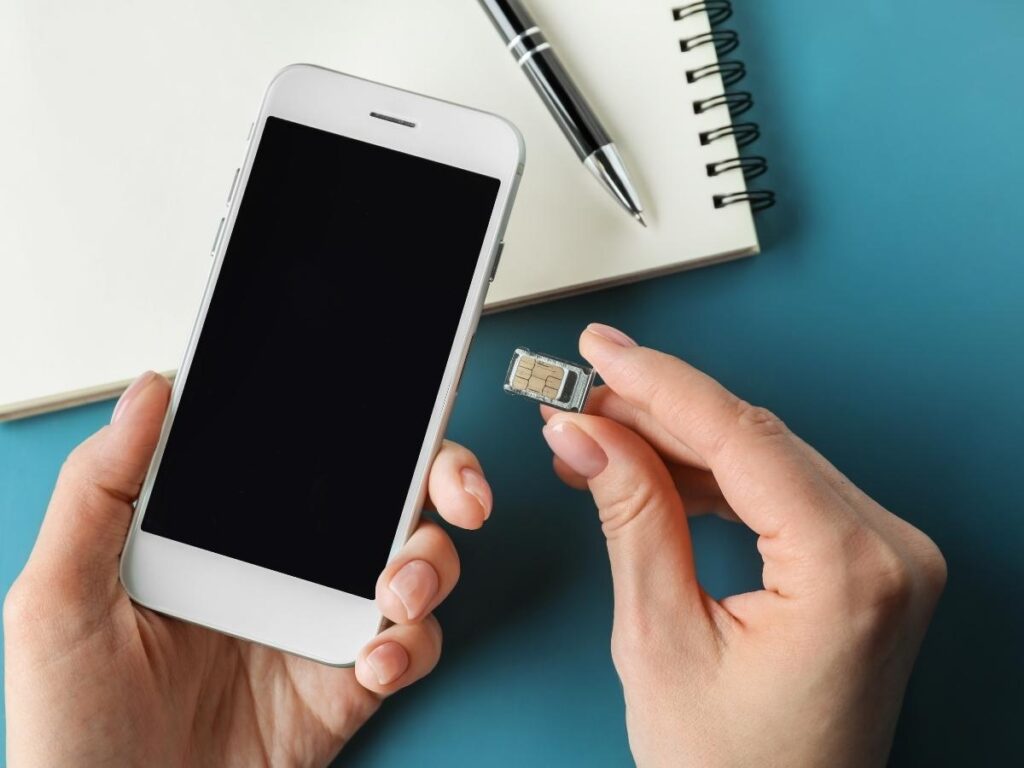 Traveler using SIM card tool to swap phone SIM card abroad.