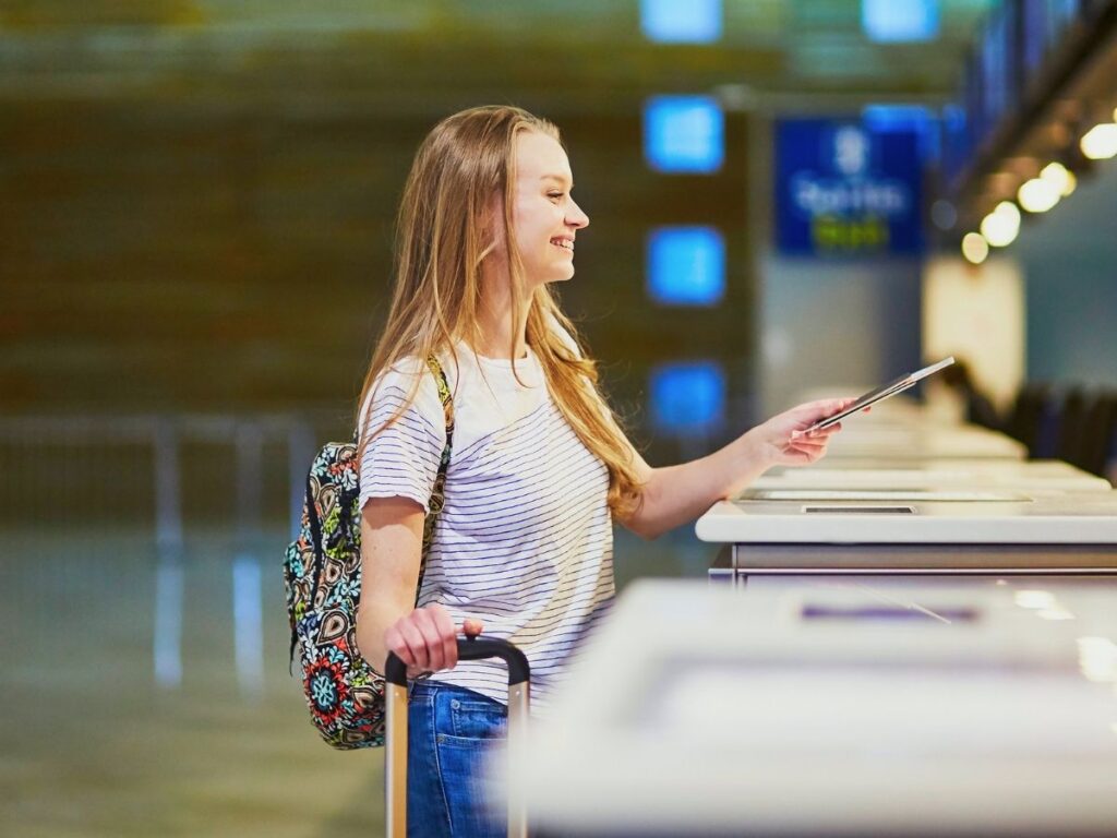 Traveler in business-casual attire smiling at airport check-in counter