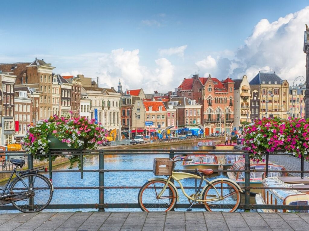 Amsterdam canal with bicycles parked on bridge and historic houses in the background at sunset